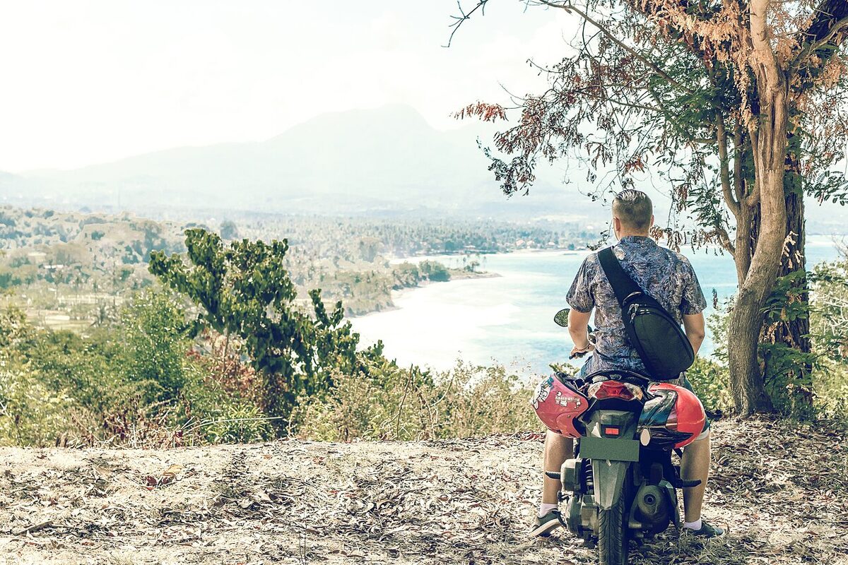 Pengendara skuter beristirahat di tepi jalan perbukitan Bali