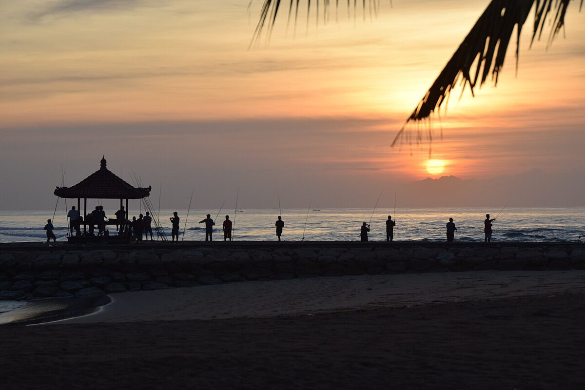 Senja di pantai Bali dengan gazebo dan pengunjung